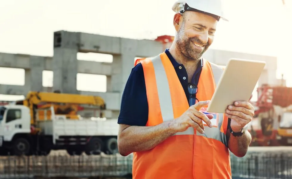 Site engineer in hi-vis checking a tablet on a construction site